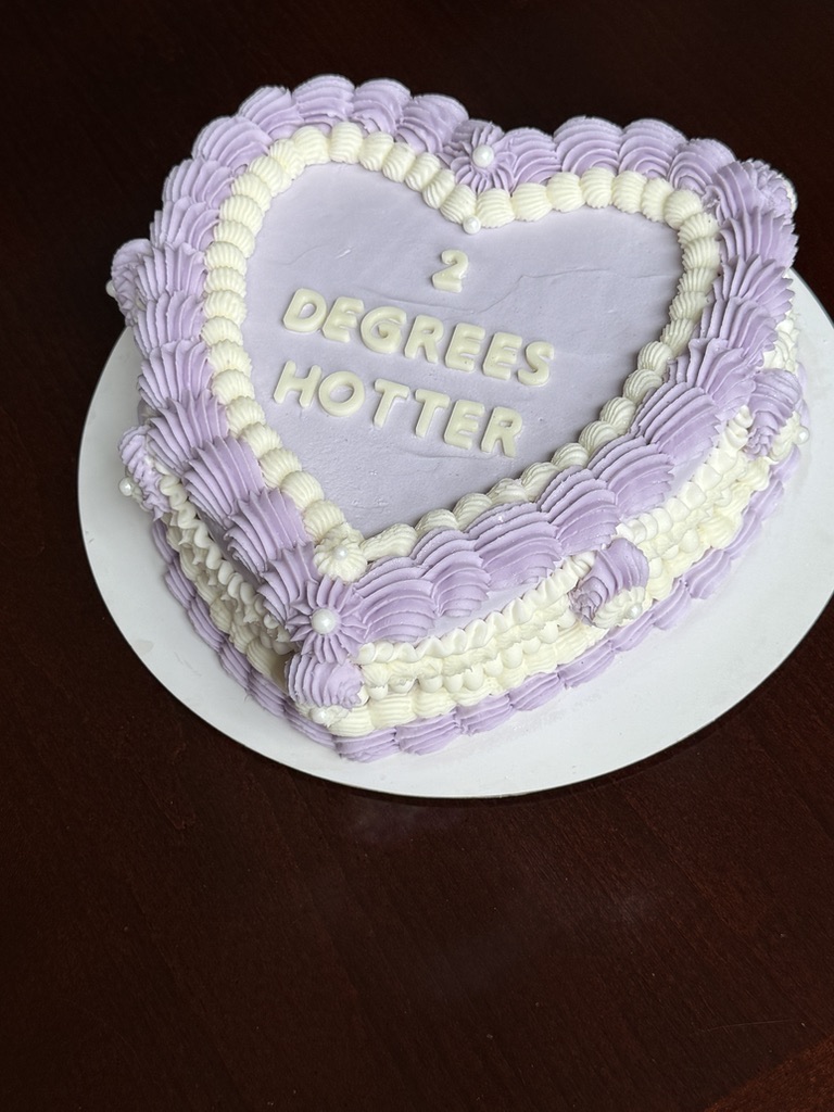Angled view of a lavender heart shaped cake with piped borders