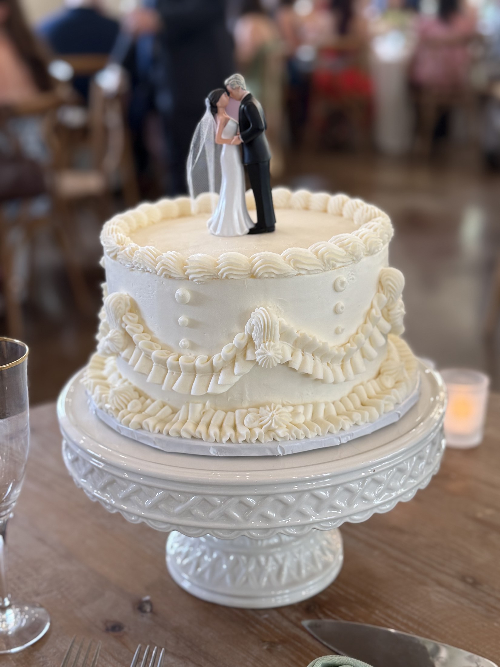 Vintage white wedding cake with piped buttercream and a bride and groom topper